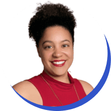 Portrait of a smiling woman with an afro, wearing a red sleeveless top and a gold necklace, against a white background.